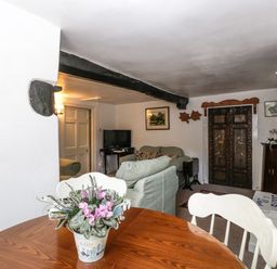 A living room with a wooden table and flower pot a sofa television and decorative wooden door at Small Piece in Porlock