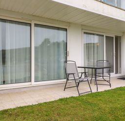A patio with two chairs and a table outside sliding glass doors at 7 Europa Court in Mawgan Porth