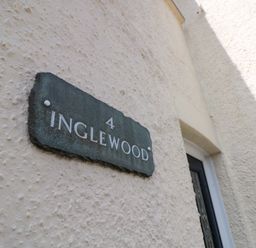A stone plaque with the number 4 and the name Inglewood on a textured exterior wall at Inglewood Keswick