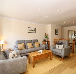 A living room with gray sofas wooden coffee table and dining table at Inglewood in Keswick