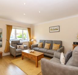 A living room with grey sofas yellow cushions wooden coffee table and a window with yellow curtains at Inglewood in Keswick