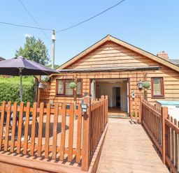 A wooden deck with a table and umbrella in front of a wooden house at Varley Villa in Newtown