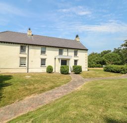 A house with a garden pathway and bushes at Clynnog House in Dwyran near Newborough