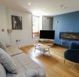 A living room with a sofa, coffee table, and television at Clynnog House in Dwyran near Newborough