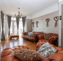 A living room with brown leather sofas and cushions wooden floor and heart-shaped wall decorations at Albany in Looe