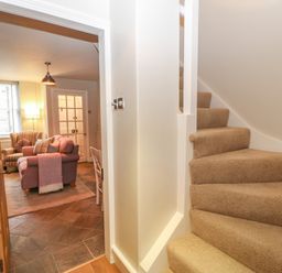 A carpeted staircase next to a living room with a sofa and an armchair at Chapel Cottage in Corbridge