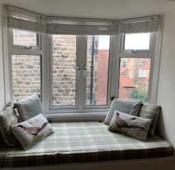 A window seat with patterned cushions and pillows in a room at A Stone's Throw in Alnmouth