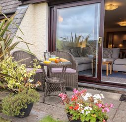A patio with wicker chairs and a table with juice and croissants outside a living room at Pavey Ark in Ambleside