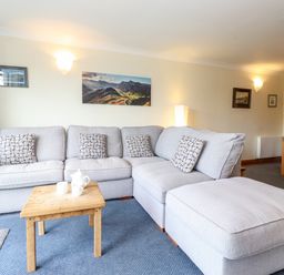 A living room with a grey sectional sofa and wooden coffee table at Pavey Ark in Ambleside