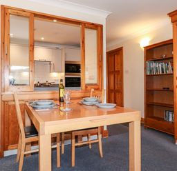 A dining area with a wooden table set for four and a bookshelf in a room at Pavey Ark in Ambleside