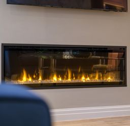A built-in rectangular electric fireplace with flames and decorative glass stones at The Neon Rose in Bowness-On-Windermere