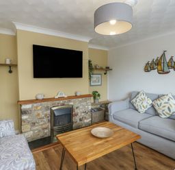 A living room with a sofa, coffee table, and television at Glasfryn Holyhead