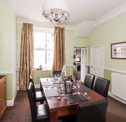 A dining room with a wooden table set for six chairs and a sideboard at Oakhurst in Keswick