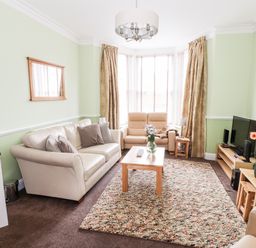 A living room with beige sofas a wooden coffee table and a television at Oakhurst in Keswick