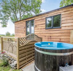 A wooden cabin with a deck and a blue hot tub outside at Stag Lodge Pod in Llanfair Caereinion