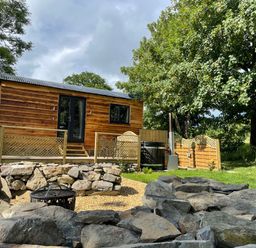A wooden pod with a deck surrounded by a fenced garden and trees at Stag Lodge Pod in Llanfair Caereinion