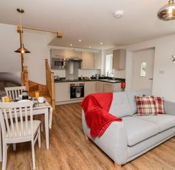 A kitchen and living area with gray sofa and dining table with chairs at The Old Mill Bake House in Goodrich