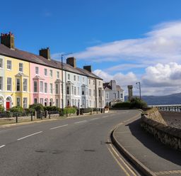 A row of pastel colored houses along a curved road by the waterfront at Lluest in Beaumaris