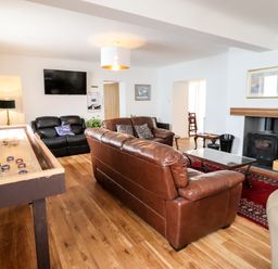 A living room with leather sofas a shuffleboard table a wall mounted television and a fireplace at The Bull Inn in Deiniolen