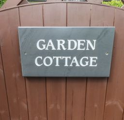 A sign with the text Garden Cottage on a brown wooden gate at Garden Cottage in Garndolbenmaen near Tremadog