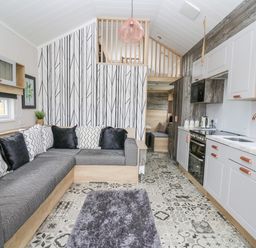 An open living room and kitchen area with a sectional sofa and patterned floor at Hares Rest in Nantmel near Rhayader