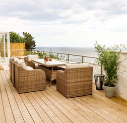 A balcony with rattan chairs and table overlooking the sea at Ocean View in Downderry