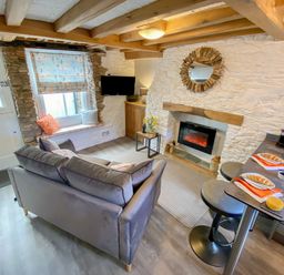 A living room with a sofa a window seat and a fireplace at Pilchard Cottage in Brixham