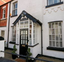 Black and white cottage entrance with glass door and windows named Rydal Cottage in Scarborough