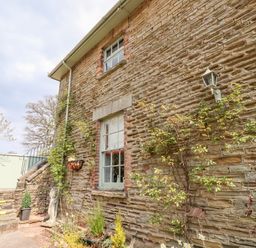 Stone exterior wall of a house with windows plants and stairs leading to a gate at The Stable in Lydney