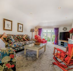 A living room with floral sofas red armchairs a coffee table and a television at Armando in Devoran Cornwall