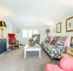 A living room with floral upholstered sofa and armchair a wooden rocking chair and coffee table at Armando in Devoran Cornwall