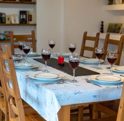 A dining table set with plates wine glasses and cutlery in a room with wooden chairs and shelves at The Old Post Office in Llandrindod Wells