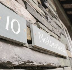 A stone wall with house number 10 and a sign saying Netherbeck in Ambleside