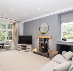 A living room with a fireplace TV and two chairs near windows at Eller Close House in Grasmere
