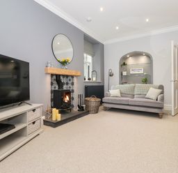 A living room with a television a wood burning stove a sofa and built in shelves at Eller Close House in Grasmere