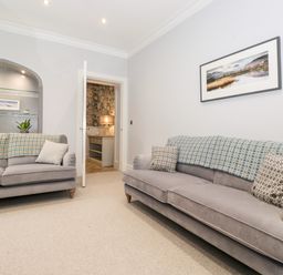 A sitting room with two sofas and a wall shelf with plants and books at Eller Close House in Grasmere