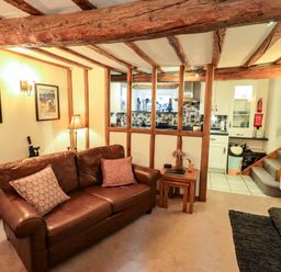 A living room with a sofa and kitchen view at Fellside Cottage in Bowness-On-Windermere