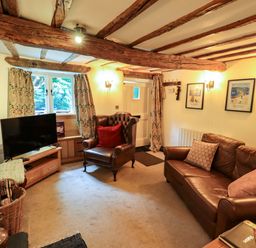 A living room with a television and sofas at Fellside Cottage in Bowness-On-Windermere