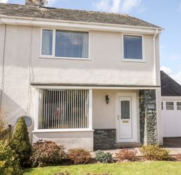 A two story house with white exterior walls a front door and large window with vertical blinds at Pooley Howe in Keswick