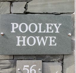 A stone wall with a sign reading POOLEY HOWE and the number 56 at Pooley Howe Keswick