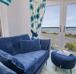 A living room with a sofa and view of the sea at Ocean View Apartment in Colwyn Bay