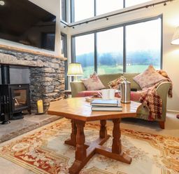 A living room with a stone fireplace and a wooden coffee table at The Badger's Shack in Garnett Bridge Longsleddale Near Kendal