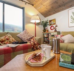 A living room with two sofas a lamp a coffee table with mugs and a French press at The Badgers Shack Garnett Bridge Longsleddale Near Kendal