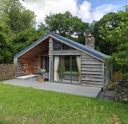 A cabin with a deck and stone chimney at The Hare's Shack in Garnett Bridge, Longsleddale. Near Kendal