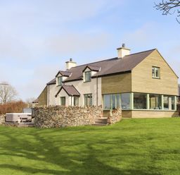 A house with stone walls and green grass in the yard at Dolwaenydd in Brynsiencyn