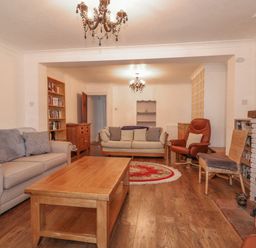 A living room with sofas chairs a wooden coffee table and a fireplace at Jobs Cottage in Snettisham