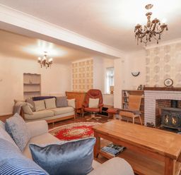 A living room with a fireplace wooden coffee table sofas an armchair and bookshelves at Job's Cottage in Snettisham