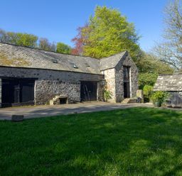 A building with a stone exterior and wooden features at Carrows Stable in Morwenstow