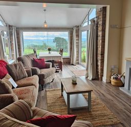 A living room with sofas and a coffee table near a dining area with a table and chairs at Sewin Cottage Golden Grove near Llandeilo