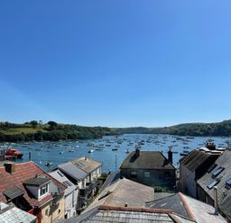 A view of rooftops overlooking boats on a river with hills in the background at The Penthouse in Salcombe